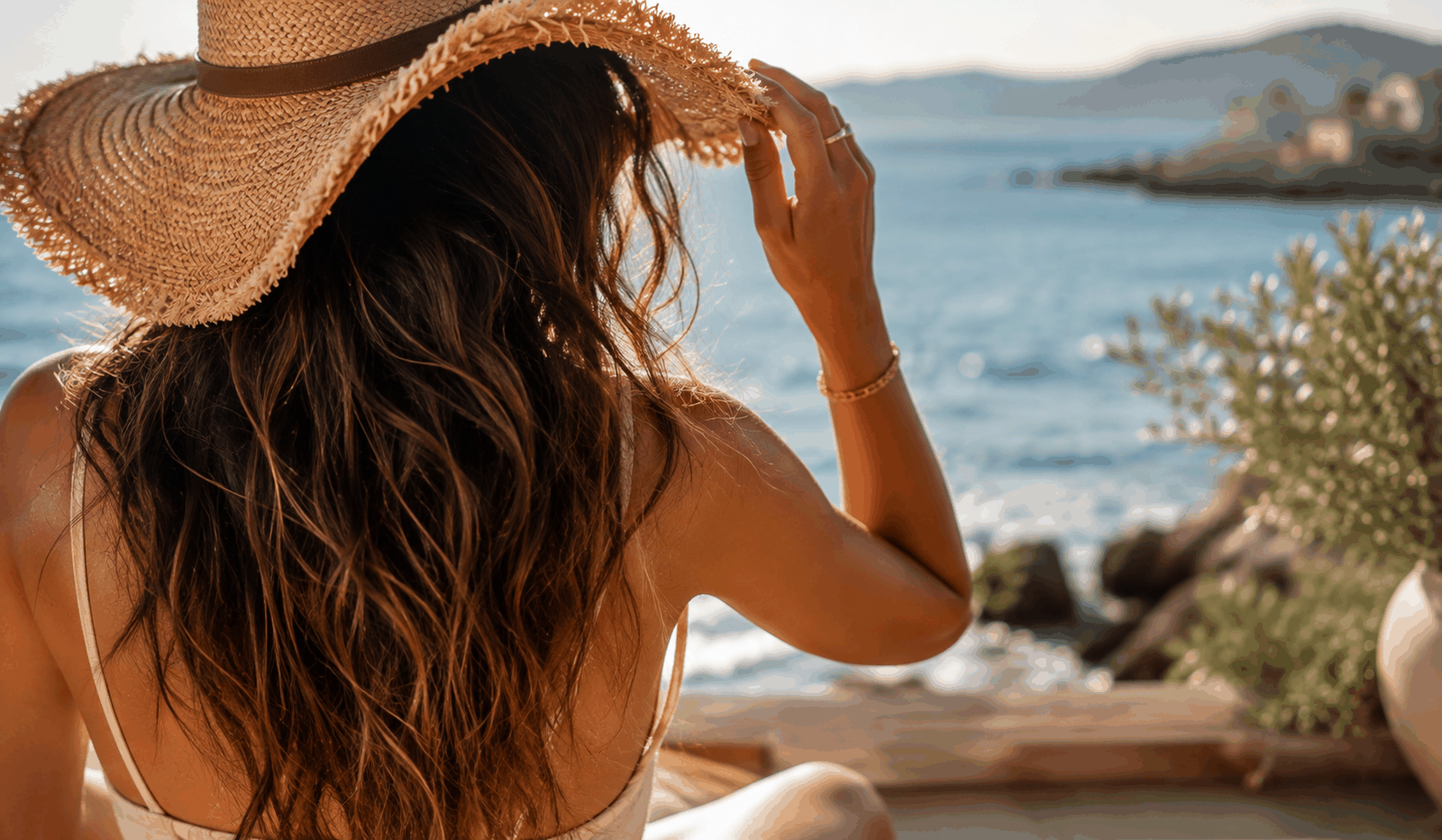 Femme aux cheveux longs protégés du soleil par un chapeau de paille au bord de la mer en été
